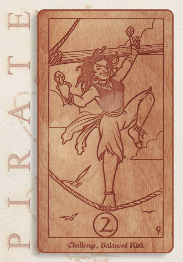 A wooden card from the Pirate Tarot shows a joyful pirate balancing on a rope with coins in each hand. Birds fly below. The card reads 2 and Challenge: Balanced Risk, with PIRATE spelled vertically in the background.