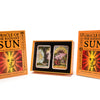 The image shows Schiffer Publishing, Ltd.'s Oracle of the Radiant Sun deck, with its box, zodiac guidebook, and two illustrated oracle cards displayed in an open case alongside two closed booklets.
