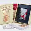 The Da Vinci Enigma Tarot (Deck and Guidebook Box Set) by Schiffer Publishing, Ltd. includes a deck in a tray, a tarot guidebook, and a box featuring Leonardo da Vinci’s sketch and red text.