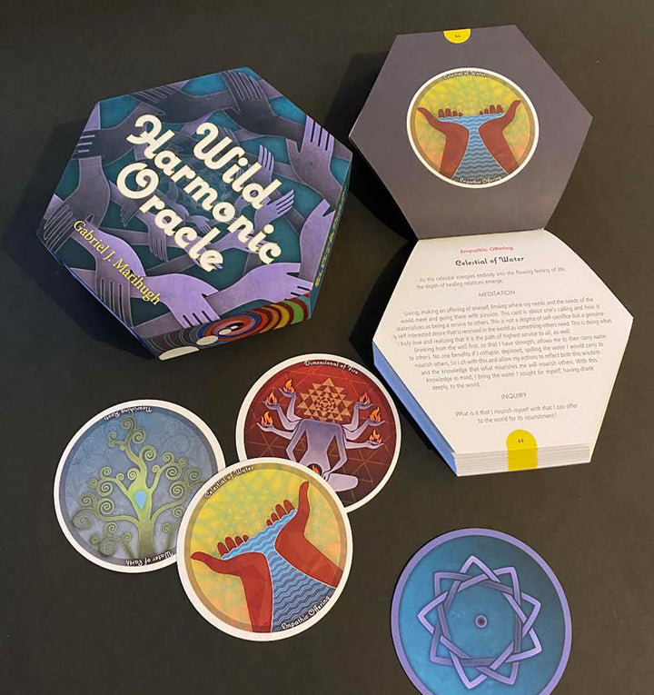 A hexagonal box labeled Wild Harmonic Oracle Cards by Schiffer Publishing, Ltd. sits open, showing colorful chakra cards with abstract designs and a booklet inside. Three alchemy-themed cards are displayed on a dark surface.