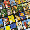 The La Santa Muerte Lenormand by Schiffer Publishing, Ltd. features colorful divination cards with unique illustrations and playing card symbols, each numbered and arranged in a grid pattern on a flat surface.