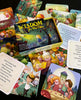A vibrant Wisdom for Wee Ones box by Schiffer Publishing, Ltd. sits open, surrounded by Proverbs cards with cheerful kids and animals, plus cards featuring uplifting quotes.