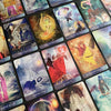 A spread of Angels of Healing and Hope Oracle cards by Schiffer Publishing, Ltd. is laid out, each featuring vibrant fantasy angel art and symbolic imagery with healing titles like “Inner Faith,” “Let Love In,” and “Sensitive Soul.”.
