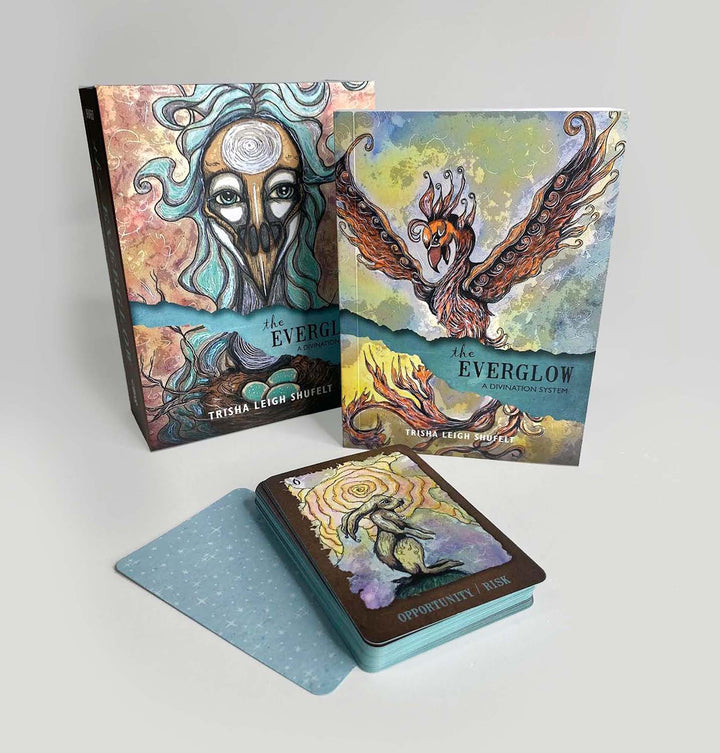 The Everglow by Schiffer Publishing, Ltd. is a divination card set with a deck, guidebook, and box featuring fantasy art—abstract mystical figures and a bird with outstretched wings. One card reads “Opportunity / Risk.”.