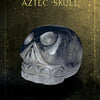 Against a textured, gold-speckled background, the Oracle of the Crystal Skulls from Schiffer Publishing, Ltd. features a stylized dark stone skull inspired by Aztec art and crystal skulls. The product name appears at the top in decorative font.