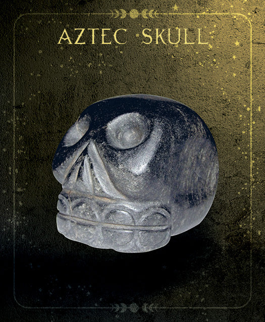 Against a textured, gold-speckled background, the Oracle of the Crystal Skulls from Schiffer Publishing, Ltd. features a stylized dark stone skull inspired by Aztec art and crystal skulls. The product name appears at the top in decorative font.