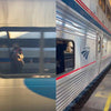 On the left, a person’s reflection appears in a train window, suggesting the quiet contemplation characteristic of studio craft and handmade skills—central themes in Craft Schools by Schiffer Publishing, Ltd. On the right, an Amtrak train is stationed beneath a platform canopy, with yellow lines highlighting the edge of the platform.