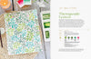 The Modern Watercolor Workshop by Schiffer Publishing, Ltd. lies open on a woven placemat, displaying botanical watercolor leaves with red berries—ideal for beginners. Nearby are paint, a green brush, candle, and towel; “Therapeutic Leaves” is shown on the right page.