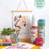 A ColorMaps Paint-by-Number Relaxing Garden display by Schiffer Publishing, Ltd. shows floral artwork, paint pots, brushes in a jar, a potted plant, rolled kits, and a completed pink flowers painting. A sign reads: Collect Both Kits!.