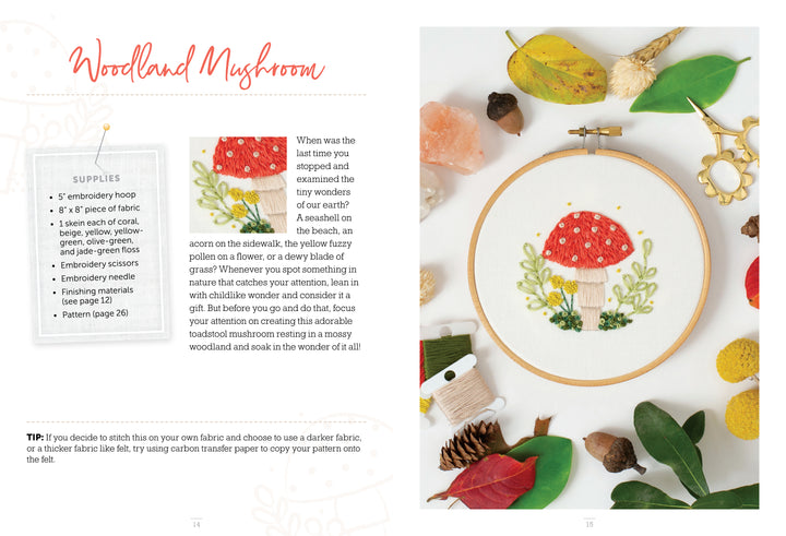 The Sunny Stitches Embroidery Kit Woodland Mushroom by Schiffer Publishing, Ltd. features a stitched red and white mushroom surrounded by grass, small flowers, and autumn leaves—perfect for creating a charming woodland embroidery scene.