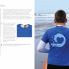 A boy on a sandy beach holds an orange surfboard, wearing a blue t-shirt with a white wave design. On the left, printmaking activity instructions from "Print It!" by Schiffer Publishing, Ltd. are visible.