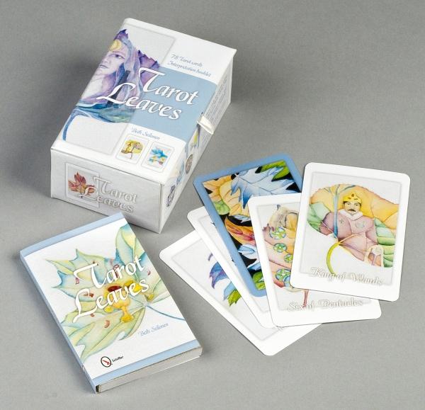 Tarot Leaves by Schiffer Publishing, Ltd. is a nature-themed tarot deck featuring watercolor-style leaf artwork. The deck, its box, and booklet are shown on a gray surface, with the box displaying the Tarot Leaves title and leaf motifs.