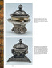 Tibetan Artifacts by Schiffer Publishing, Ltd.: Two ornate antique silver kapalas with lids—one on a round tripod base with faces, the other on a square base with lion and floral motifs—are photographed on a light background.