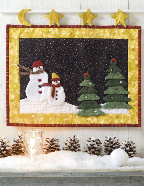 Christmas Magic" by Schiffer Publishing, Ltd. is a festive quilted wall hanging with two snowmen and three trees on a snowy hill, bordered by yellow stars—perfect for holiday décor and Christmas patchwork projects.