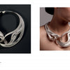 The book "Chinese Contemporary Jewelry Design" by Schiffer Publishing, Ltd. features a sculptural silver necklace with wave-like curves, shown both on a black background and worn to highlight its intricate, modern style.